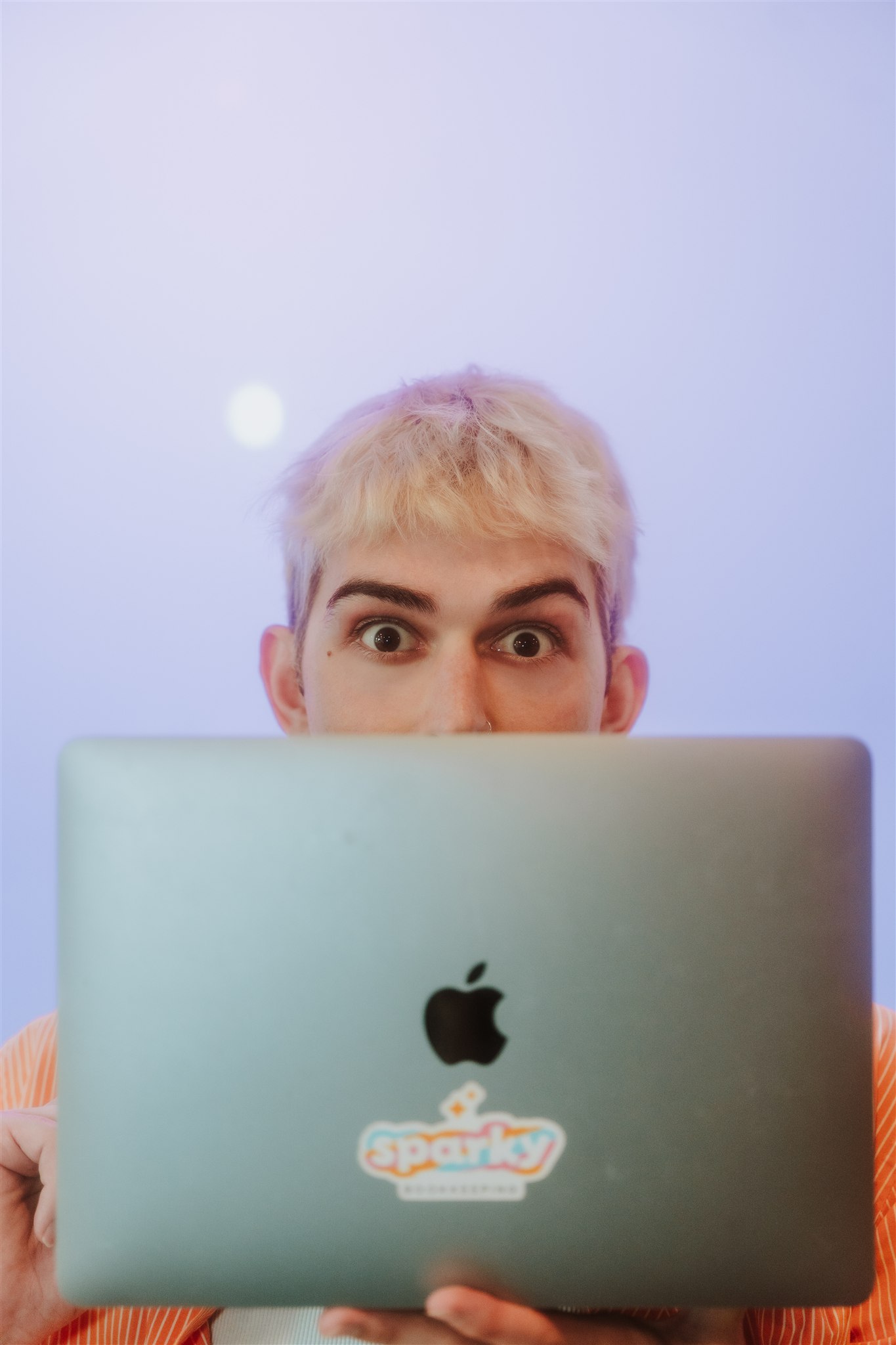 blond man staring over computer with wide eyes
