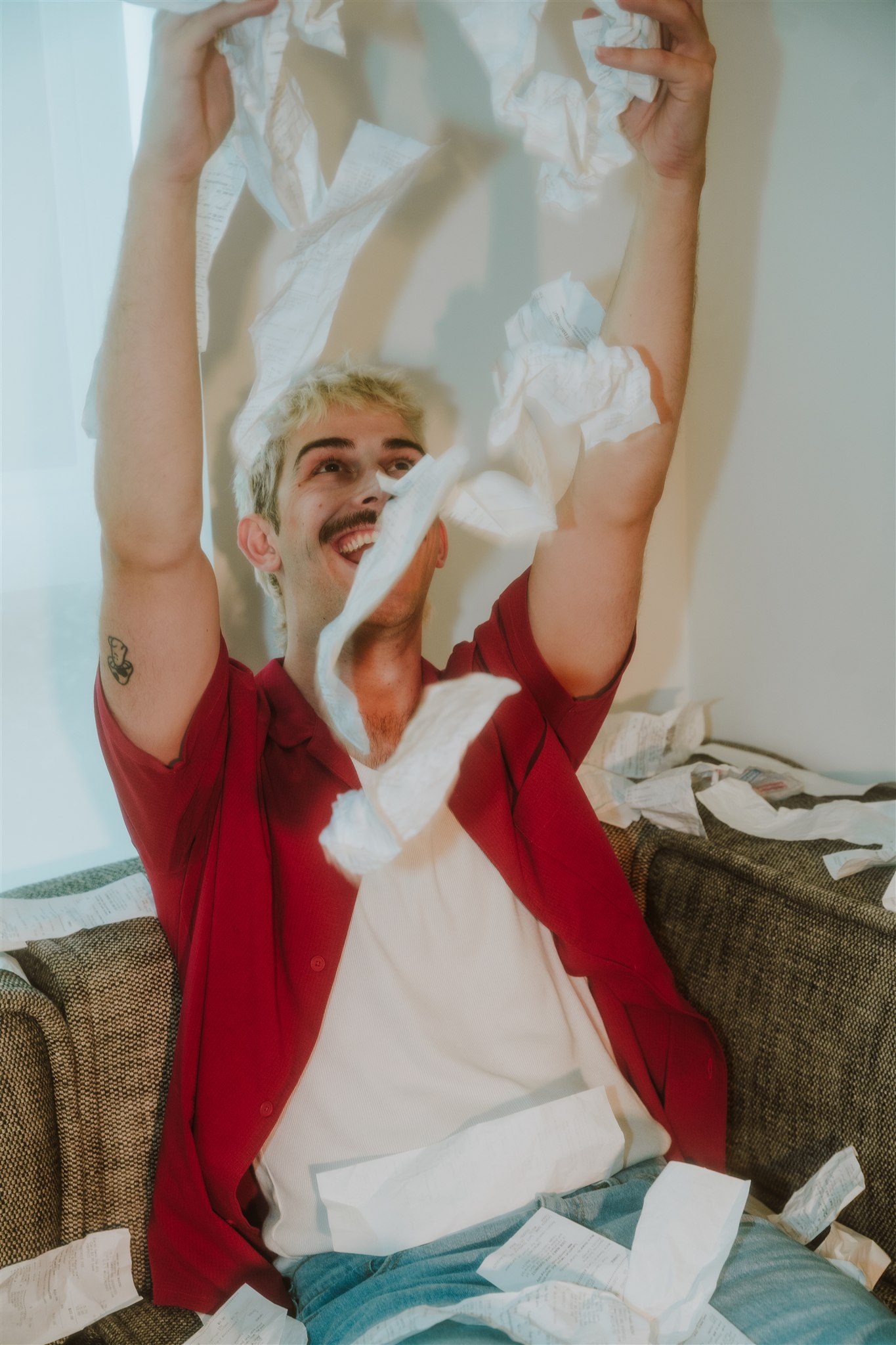 Man sitting on a couch throwing receipts in the air